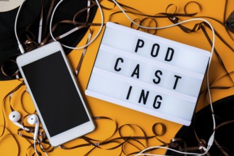 Podcasting lettering and vinyl record audio cassette tape album headphones and mobile phone.