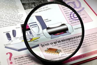 Magnifying glass on a book of explanations on the invention of the computer