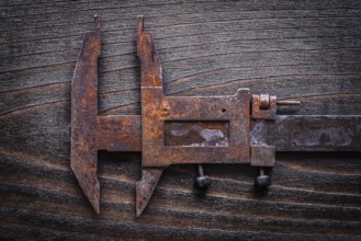 Rusted old-fashioned measuring slide caliper on vintage wooden board construction concept