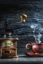 Steamy coffee cup and mill on vintage wood