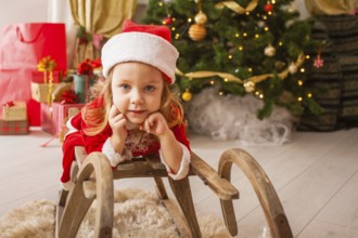 Little child in christmas hat dreaming about christmas miracle. Girl makes a wish an new year night