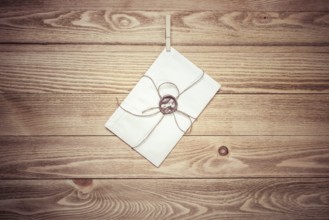 Envelope hanging on rope on wooden background