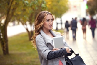 A businesswoman with a tablet walking in a city park