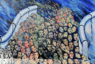 A multitude of surreal painted faces crowd together, surrounded by blue and bright colours,