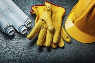 Working gloves with yellow helmet and rolled blueprints