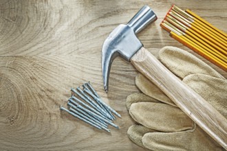 Set of protective gloves wooden meter claw hammer nails on wood board construction concept