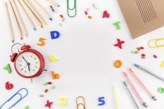 Creative flat lay back to school concept with alarm clock, color school and office supplies on