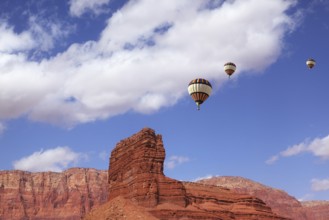 Huge balloons with the passenger basket flying over the picturesque cliffs of red sandstone