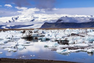 Cold day in July. Arctic Circle, Iceland. White and blue icebergs and ice floes reflected in the