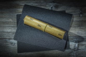 Roll of sandpaper and sheets of it on vintage wood