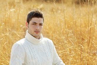 Autumn winter man portrait in outdoor dried grass field with turtleneck sweater