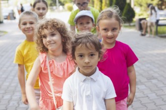 Portrait of happy preschool kids posing closely together outdoors, looking at camera. Lovely boy