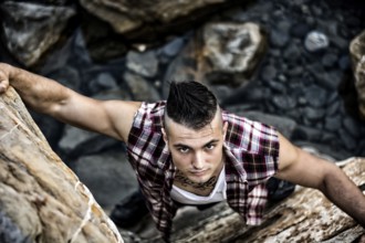 Three Quarter Shot of an Attractive Athletic Young Man Climbing a Rock at the River or by the Sea