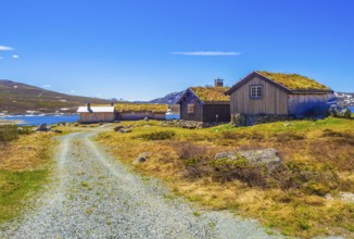 Amazing Vavatn lake panorama rough landscape view cottages and mountains with snow during summer in