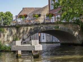 Picturesque stone bridge with flower boxes in bloom over a quiet canal, Bruges, Flanders, Belgium,