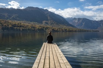 Sitting on a small jetty and enjoying the view on the landscape of lake Bohinj in the Triglav