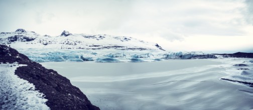 Huge majestic glacier's icy surface by snowy mountain in Iceland