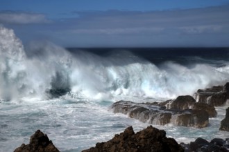 Waves breaking thunderously on the sharp rocks of a cliff. Landscape format. Waves breaking