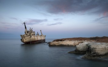 Abandoned Ship on the rocky coast with beautiful blue and orange morning colors creating an exotic