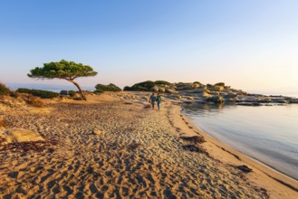 Vourvourou, Sithonia, Greece, September 17, 2019: Couple walking at sunrise Karidi beach.