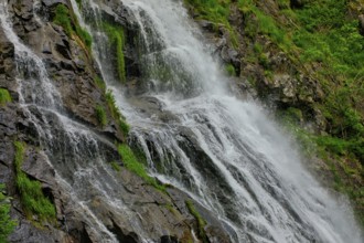 Close-up of a waterfall flowing over moss-covered rocks and conveying freshness, waterfall,