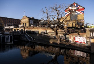 A beautiful canal scene with a building adorned with a British flag, a leafless tree, and