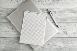 White paper Notepad and laptop on vintage shabby white wooden background. the view from the top.