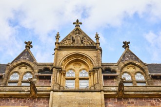 Detailed, gothic facade sculptures of a historic manor house against a clear blue sky.