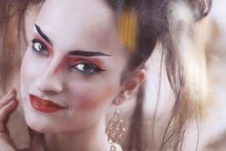 Close up stylized portrait of a Japanese geisha with bright make up standing at the window watching