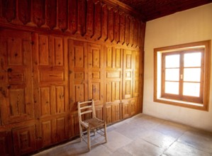 Empty room with wooden wall one chair on the floor, and bright sunshine through the open window