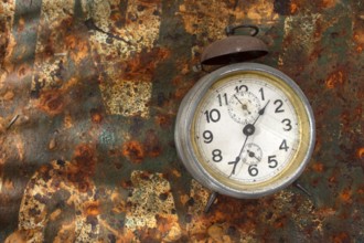 Old alarm clock resting on rusty metallic background