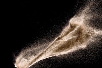 Dry river sand explosion. Golden colored sand splash against dark background