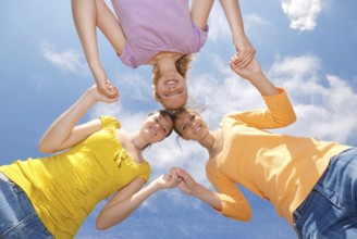 Group of three friends smiling with heads together looking at camera. Low angle view