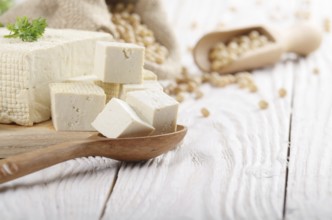 Soy Bean curd tofu on cutting board and in hemp sack on white wooden kitchen table. Space for text