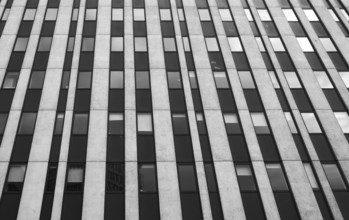 Close up perspective detail of tall high rise brutalist style office building with white vertical
