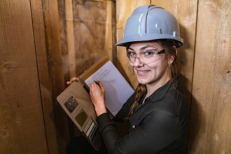 Indoor air quality inspector woman looking for molds or fungi problems on wooden walls and taking