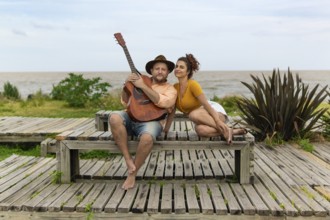 Couple of musicians sitting on the beach looking at the camera