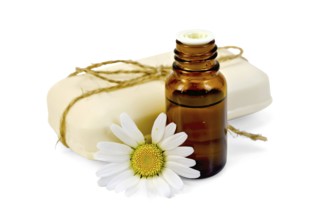 Oil in a bottle, a bar of white soap, tied with twine, daisy flower isolated on white background