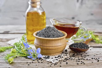 Flour of black caraway in a bowl, seeds in a spoon, oil in a bottle and sauceboat on burlap, sprigs