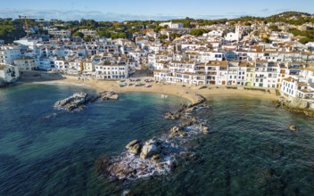 Aerial view of a picturesque coastal town with white buildings, sandy beach, and clear blue sea
