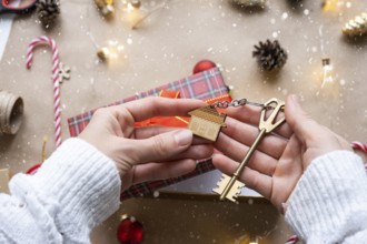 Key to house with keychain on cozy home in gift box with Christmas decor packaging. Pack present