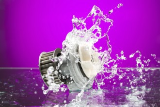 Auto parts, engine cooling pump in spurts of water on purple gradient background