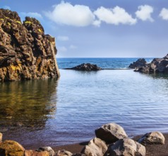 The stony shore of the Atlantic ocean. Small bay with smooth water. Volcanic island of Madeira. The