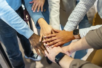 Coworkers joining hands in unity, symbolizing teamwork and collaboration in a modern coworking