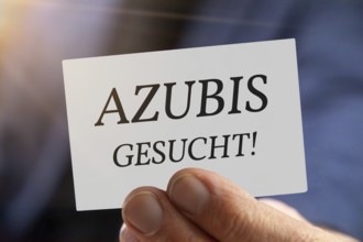 Trainee wanted: Close-up of a man with a business card AZUBI GESUCHT (symbolic image, composing)