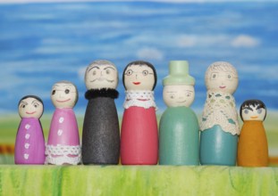 Seven funny painted wooden cones man and woman, big and small in front of a colourful painted