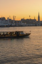 A ship on a river at sunset with the city silhouette in the background, Hamburg, Germany