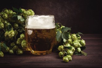 A mug of beer, on a wooden table, with a branch of fresh hops, rustic, no people