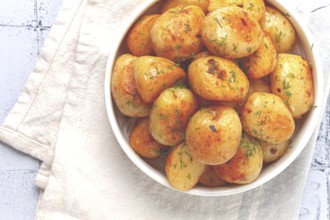 Baked new potatoes, with butter and dill, on a white plate, at home, no people