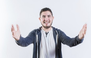 Friendly young man welcoming with open arms isolated. Hospitable guy opening arms to the camera